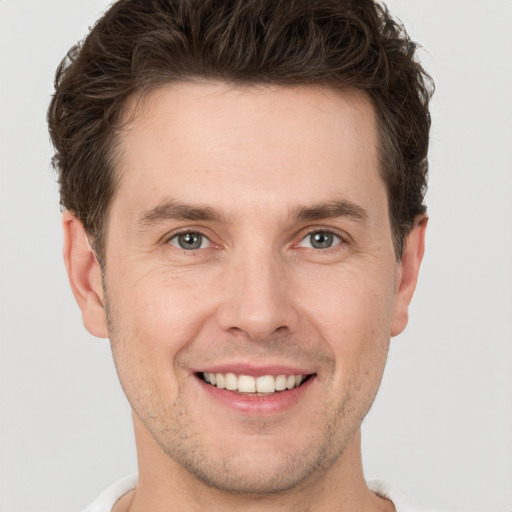 Joyful white young-adult male with short  brown hair and grey eyes