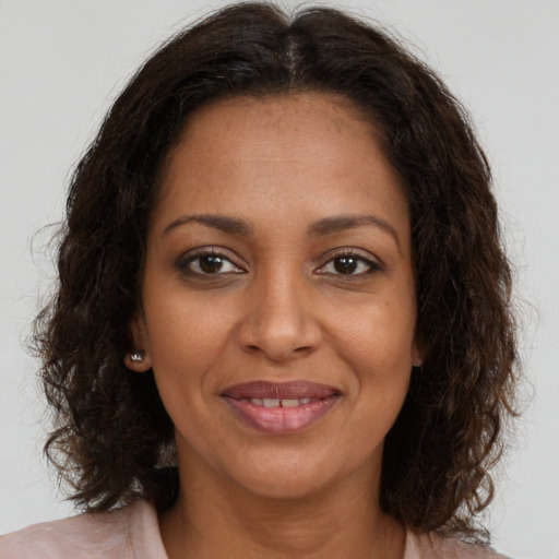 Joyful black young-adult female with long  brown hair and brown eyes