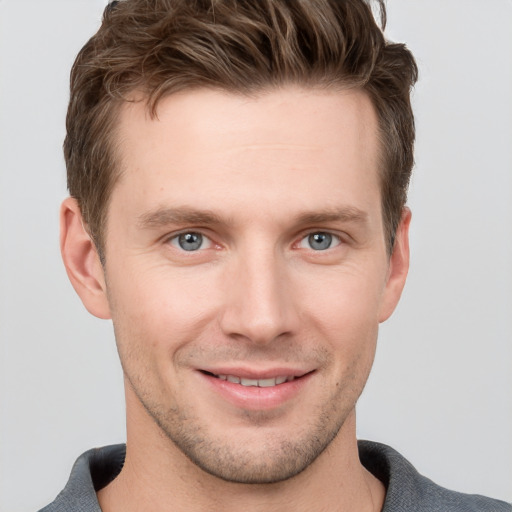 Joyful white young-adult male with short  brown hair and grey eyes