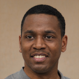 Joyful black young-adult male with short  black hair and brown eyes