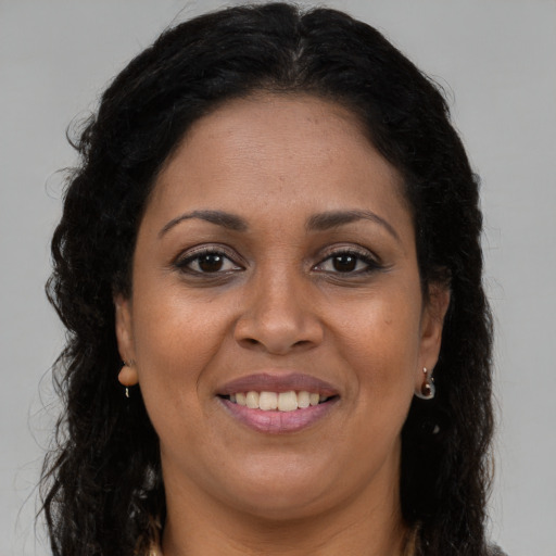 Joyful black adult female with long  brown hair and brown eyes