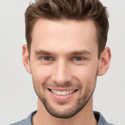 Joyful white young-adult male with short  brown hair and grey eyes