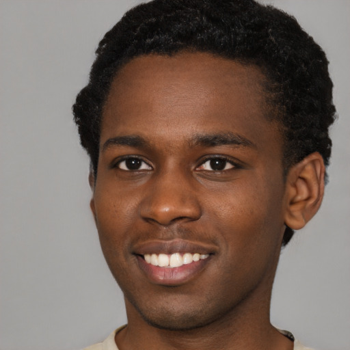Joyful black young-adult male with short  brown hair and brown eyes