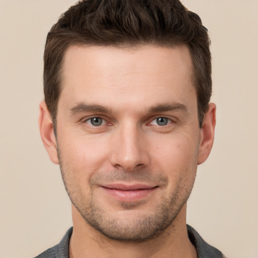 Joyful white young-adult male with short  brown hair and grey eyes