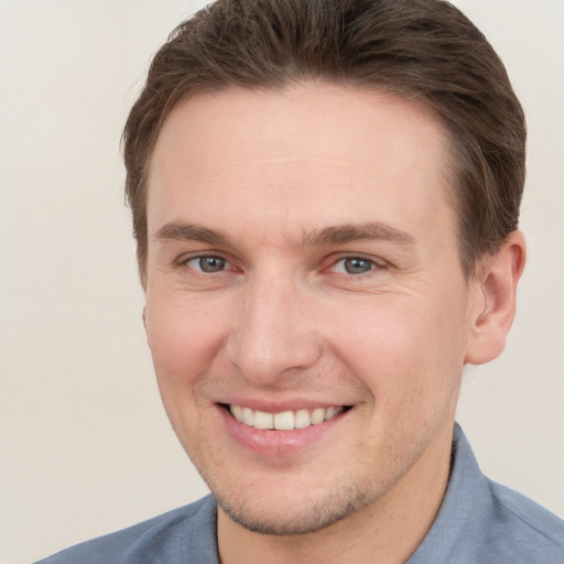 Joyful white young-adult male with short  brown hair and grey eyes