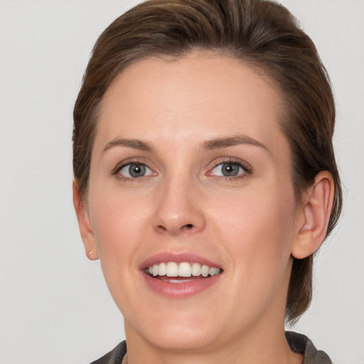 Joyful white young-adult female with medium  brown hair and grey eyes