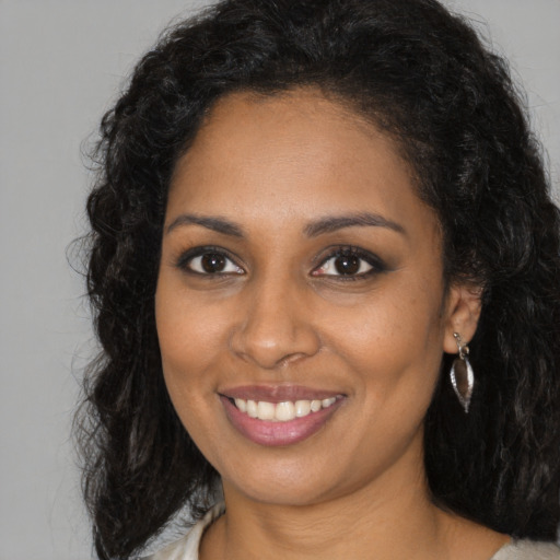 Joyful black young-adult female with long  brown hair and brown eyes