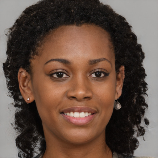 Joyful black young-adult female with long  brown hair and brown eyes