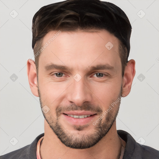 Joyful white young-adult male with short  brown hair and grey eyes