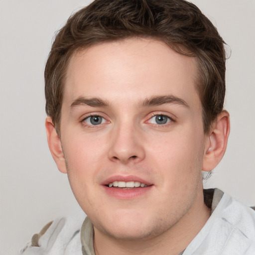 Joyful white young-adult male with short  brown hair and blue eyes