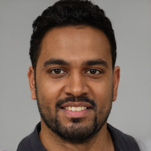 Joyful black young-adult male with short  black hair and brown eyes