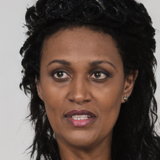 Joyful black adult female with long  black hair and brown eyes