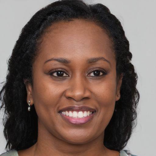 Joyful black adult female with long  brown hair and brown eyes