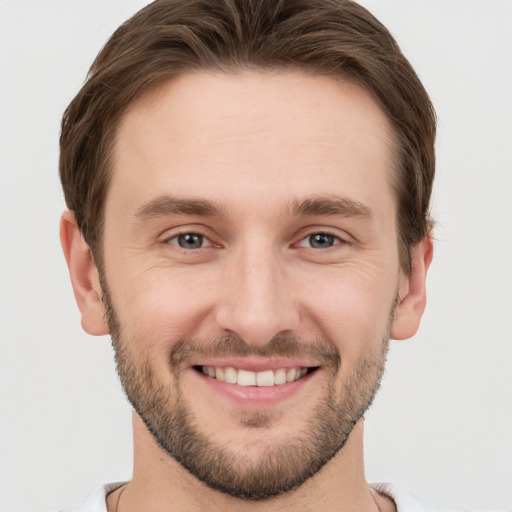 Joyful white young-adult male with short  brown hair and grey eyes