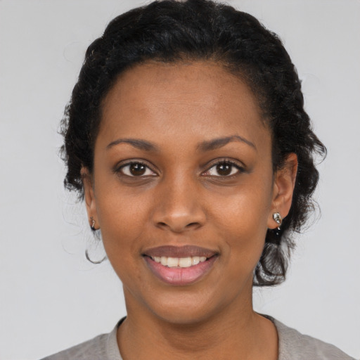 Joyful black young-adult female with short  black hair and brown eyes