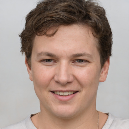 Joyful white young-adult male with short  brown hair and grey eyes