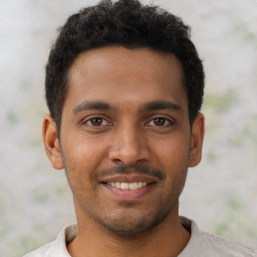 Joyful black young-adult male with short  brown hair and brown eyes
