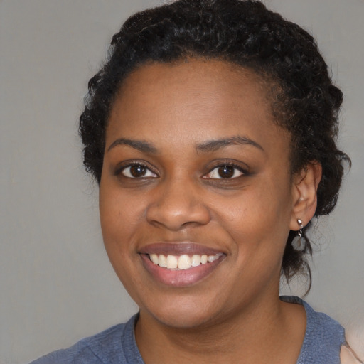 Joyful black young-adult female with medium  black hair and brown eyes