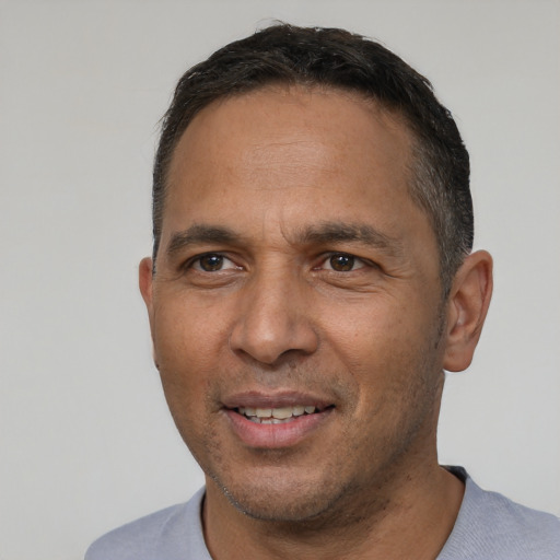 Joyful latino adult male with short  black hair and brown eyes