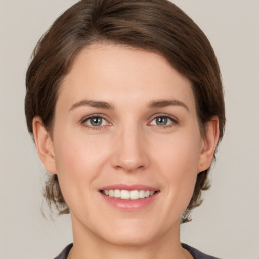 Joyful white young-adult female with medium  brown hair and grey eyes