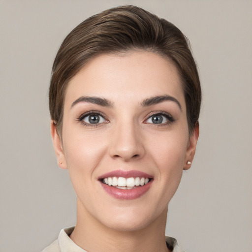 Joyful white young-adult female with short  brown hair and grey eyes