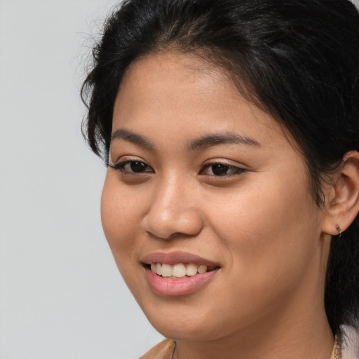 Joyful latino young-adult female with medium  brown hair and brown eyes