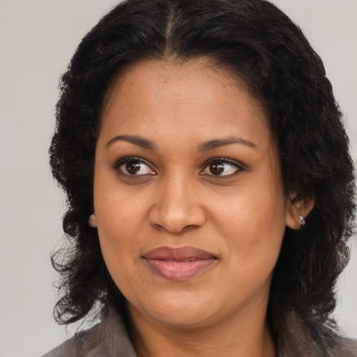 Joyful black young-adult female with long  brown hair and brown eyes