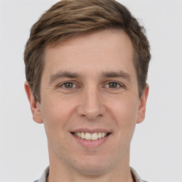 Joyful white young-adult male with short  brown hair and grey eyes