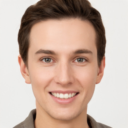 Joyful white young-adult male with short  brown hair and grey eyes