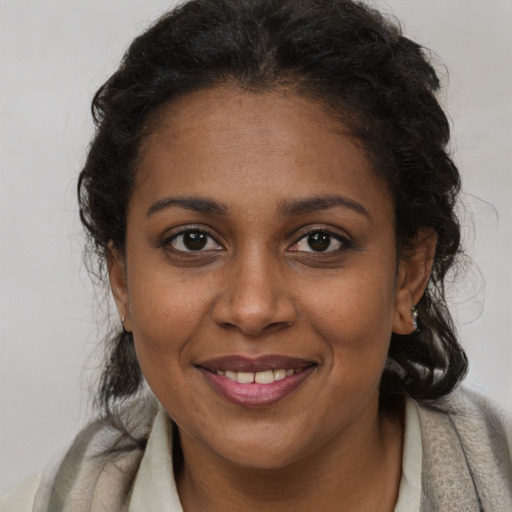 Joyful black young-adult female with long  brown hair and brown eyes