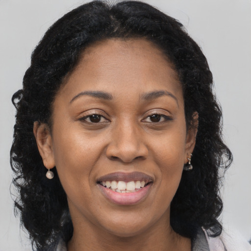 Joyful black young-adult female with long  brown hair and brown eyes