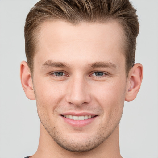 Joyful white young-adult male with short  brown hair and grey eyes