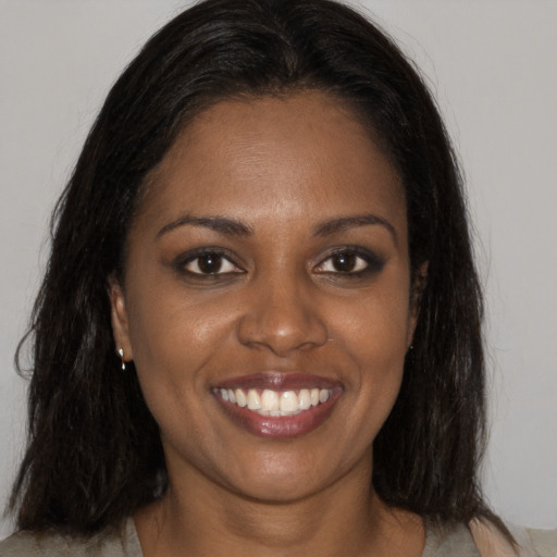 Joyful black young-adult female with long  brown hair and brown eyes