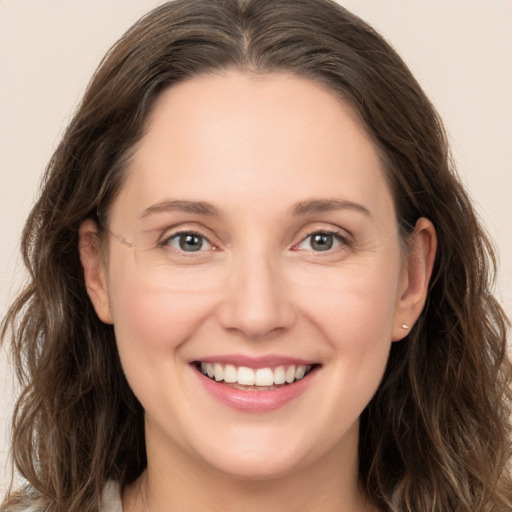 Joyful white young-adult female with long  brown hair and grey eyes