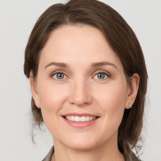 Joyful white young-adult female with medium  brown hair and grey eyes