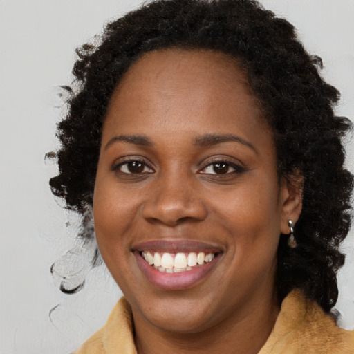 Joyful black young-adult female with long  brown hair and brown eyes