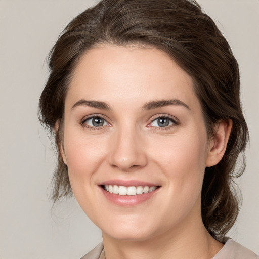 Joyful white young-adult female with medium  brown hair and grey eyes