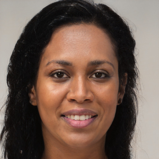 Joyful black young-adult female with long  brown hair and brown eyes