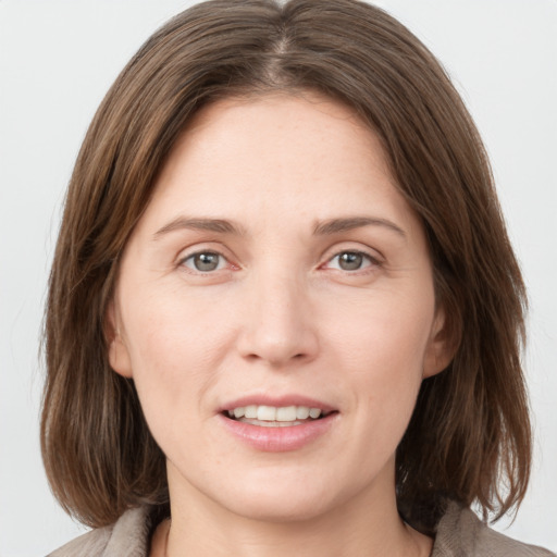 Joyful white young-adult female with medium  brown hair and grey eyes