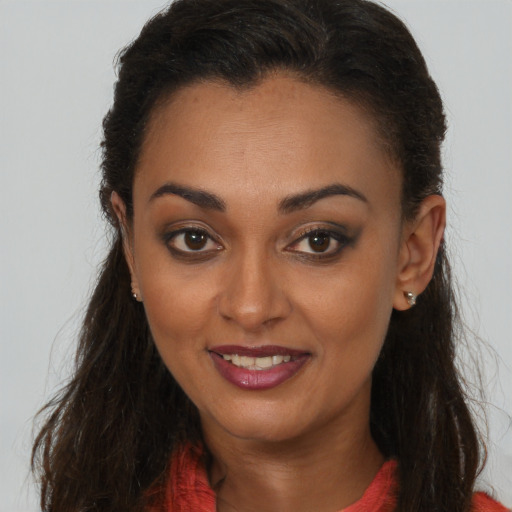 Joyful black young-adult female with long  brown hair and brown eyes