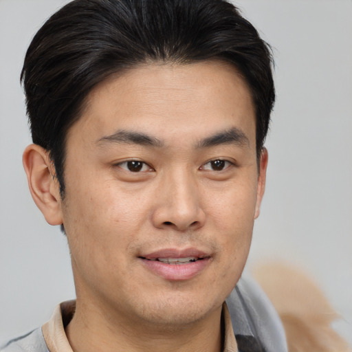 Joyful asian young-adult male with short  brown hair and brown eyes