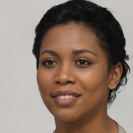 Joyful black young-adult female with short  black hair and brown eyes