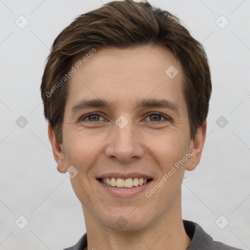 Joyful white young-adult male with short  brown hair and grey eyes