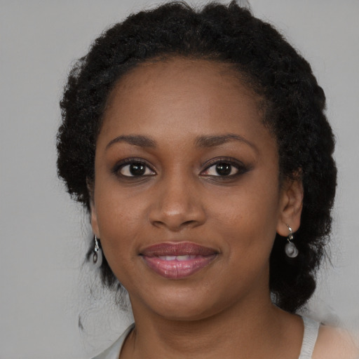 Joyful black young-adult female with long  brown hair and brown eyes
