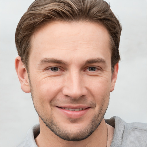 Joyful white young-adult male with short  brown hair and grey eyes