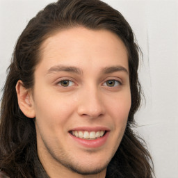 Joyful white young-adult male with long  brown hair and brown eyes