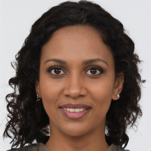 Joyful black young-adult female with long  brown hair and brown eyes