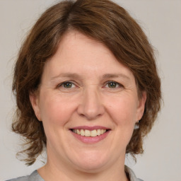 Joyful white adult female with medium  brown hair and green eyes