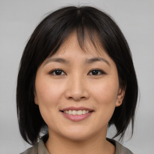 Joyful asian young-adult female with medium  brown hair and brown eyes