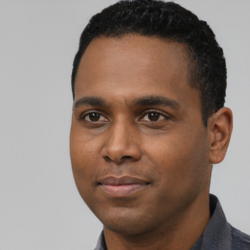 Joyful black young-adult male with short  black hair and brown eyes